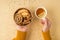 First person top view photo of hands in sweater holding cup of tea with lemon and wooden bowl with cookies dried lemon slices