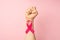 First person top view photo of raised female hand with clenched fist and pink ribbon on wrist symbol of breast cancer awareness on