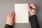 First person top view photo of woman`s hands holding pen open copybook on  grey background with blank space