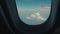 First-person view. Aircraft in the sky. Clouds outside the window or porthole of an airplane. Airplane wing at great heights with