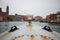 First person view of ancient rusty metal boat with old italian venice city and river scape cloudy Sky