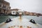 First person view of ancient rusty metal boat with old italian venice city and river scape cloudy Sky