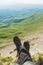 A first-person view POV of a man sits on the edge of a high cliff and enjoys the scenery. Wide angle human foot trekking