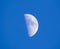 A first quarter moon against a blue sky