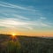 The first rays of the rising sun in a field on the outskirts of the city