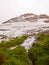 First snow in Alps touristic region. Fresh green meadow with rapids stream. Peaks of Alps mountains in background.