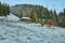 The first snow delicately blankets the landscape, while an isolated wooden cabin stands amidst the picturesque scenery