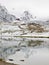 First snow in mountains. Autumn lake in Alps with mirror level. Misty sharp peaks of high mountains