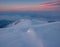 The first sunlight on the mountains shines through the fog and clouds. Snow-covered hills with dramatic scenery.