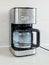 The first use of drip-type coffee maker should be with clean water without coffee. Red button indicates process is going on.