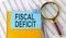 FISCAL DEFICIT text on sticker on notebook with magnifier and chart. Business concept