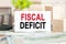 FISCAL DEFICIT text on white paper, on the background of bills and wooden blocks, business concept