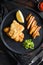 Fish & chips with dip and lemon black plate with British traditional cusine food with beer-battered cod and fries and a side of