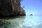 Fish in the clear Caribbean sea under a blue sky by a rock outcropping