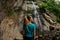 Fish-eye photo rear view girl standing and looking at the beautiful waterfall in the forest