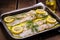 fish fillet marinated with lemon wedges and fresh herbs