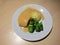 Fish meat topped with sauce and boiled broccoli, one scoop of mash potato in the white dish.