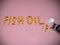 Fish oil lettering lined with fish oil capsules on pink background.