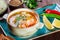 Fish soup with salmon and shrimps, dill, potatoes, lemon, peppers and bread on dark wooden background,