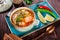 Fish soup with salmon and shrimps, dill, potatoes, lemon, peppers and bread on dark wooden background, healthy food.