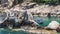 Fisher boat moving on waves at anchor between huge stone blocks in Tanote Bay, Koh Tao Island, Thailand.