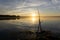 Fisher man fishing with spinning rod on a river bank at misty foggy sunrise