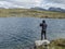 Fisherman, angler figure at northern landscape, tundra in Swedish Lapland with blue artic lake, green hills and