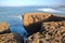 A fisherman angling above the high cliffs near Amoreira beach Aljezur, Costa Vicentina, Algarve