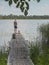 Fisherman back on old wood pier over lake water in summer