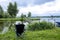 A fisherman in a cap sits in a chair near the lake with a fishing rod and catches fish