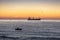Fisherman and cargo ship sailing in the sea on sunrise
