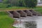 A fisherman catches fish against the background of an old wooden sluice on the Tikhvinka River