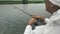 Fisherman catches fish. Man fishing with spinning rod on lake. Male hands catching fish and tightens a fishing line reel. Handle r