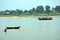 A fisherman catching fish in the river and a boat carrying passengers.