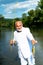 Fisherman caught a trout fish. Portrait of cheerful senior man fishing. Grandfather with catch fish. Mature man