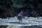A fisherman crosses the Capilano River to fish for Steelhead with a fly-fishing rod