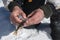 Fisherman hands holding perch and removing its skin of a frozen lake in the mountain