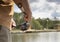 Fisherman hands holding reel rod, spoon-bait and fishing over lake, close up