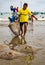 Fisherman hauls flounders onto beach