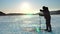 a fisherman makes a hole in the ice for winter fishing. Sunset on winter lake.