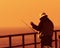 Fisherman on pier at sunset