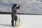 Fisherman pulls an ice drill out of the ice on a reservoir in winter