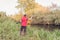 Fisherman in a red vest with a fishing rod on the shore