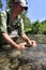 Fisherman releasing little trout in river