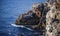 Fisherman on the rock, High inaccessible coastal cliffs made of shell rock