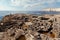 Fisherman on rocky cliff standing alone. Landscape with blue sea around island and cavernous rocks