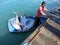 A fisherman on a rowboat full of huge freshly caught tuna delivering fish from the ship to the market in the capital city.