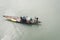 A fisherman rowing his narrow fishing boat in the Ganges river. Commercial fishing net on his nautical vessel. Rural scene. High