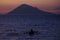 Fisherman sail alone when dusk with the background of Manado Tua Island