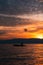 Fisherman sailing on the wavy ocean under the gleaming  sunset piercing through the clouds